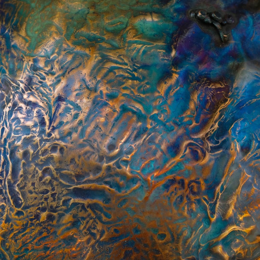 Flame patina across a hammered copper surface